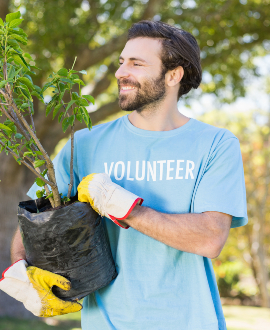 A volunteer man holding plant in park